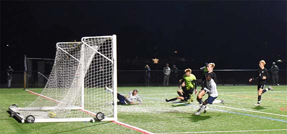 Joey Aman (left) slides in celebration as teammate Daniel Fombu scores in the United East Championship Game.